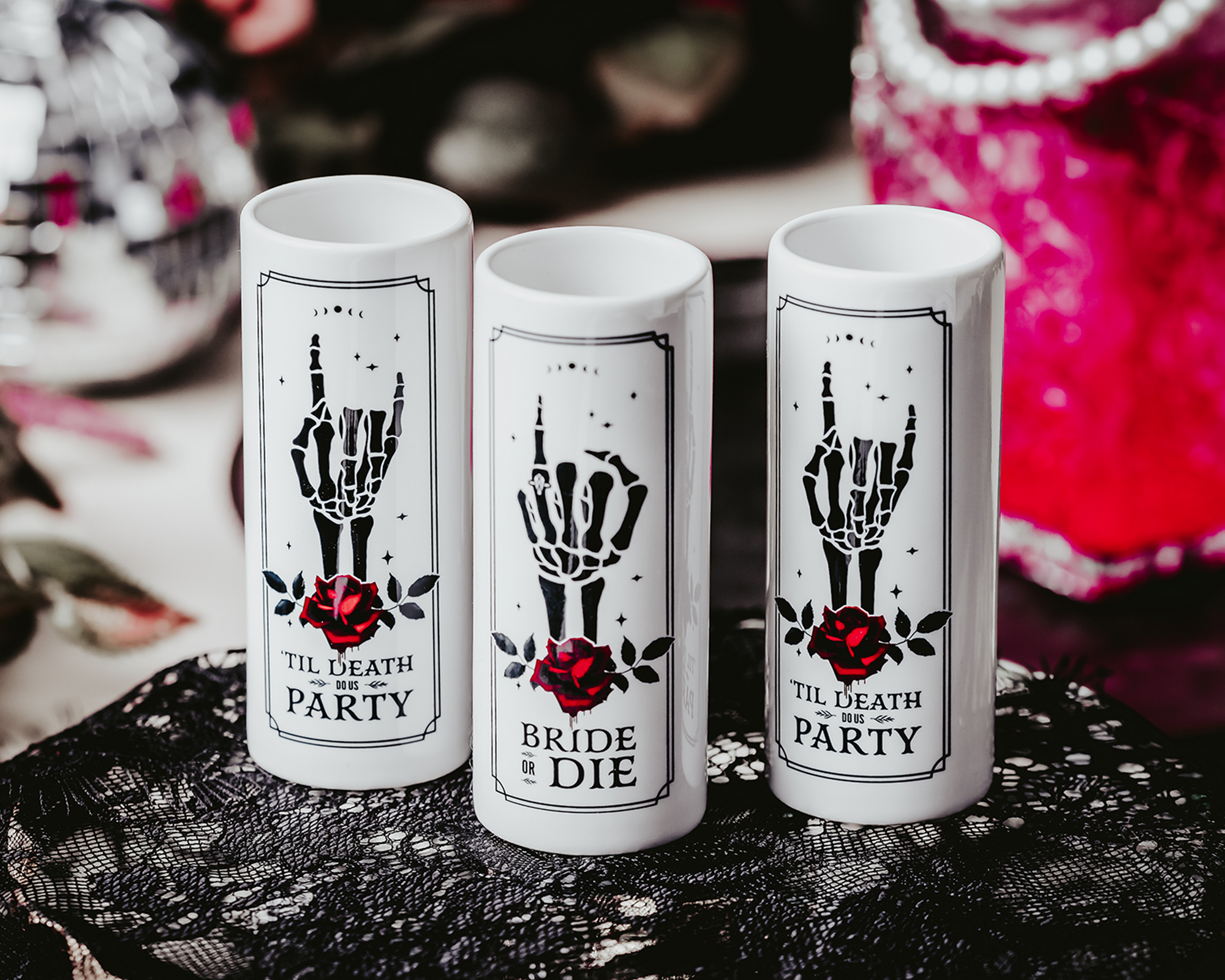 Gothic-style ceramic shot glasses featuring skeleton hand designs with red roses and phrases like "Bride or Die" and "'Til Death Do Us Party," perfect for an alternative bridal party.