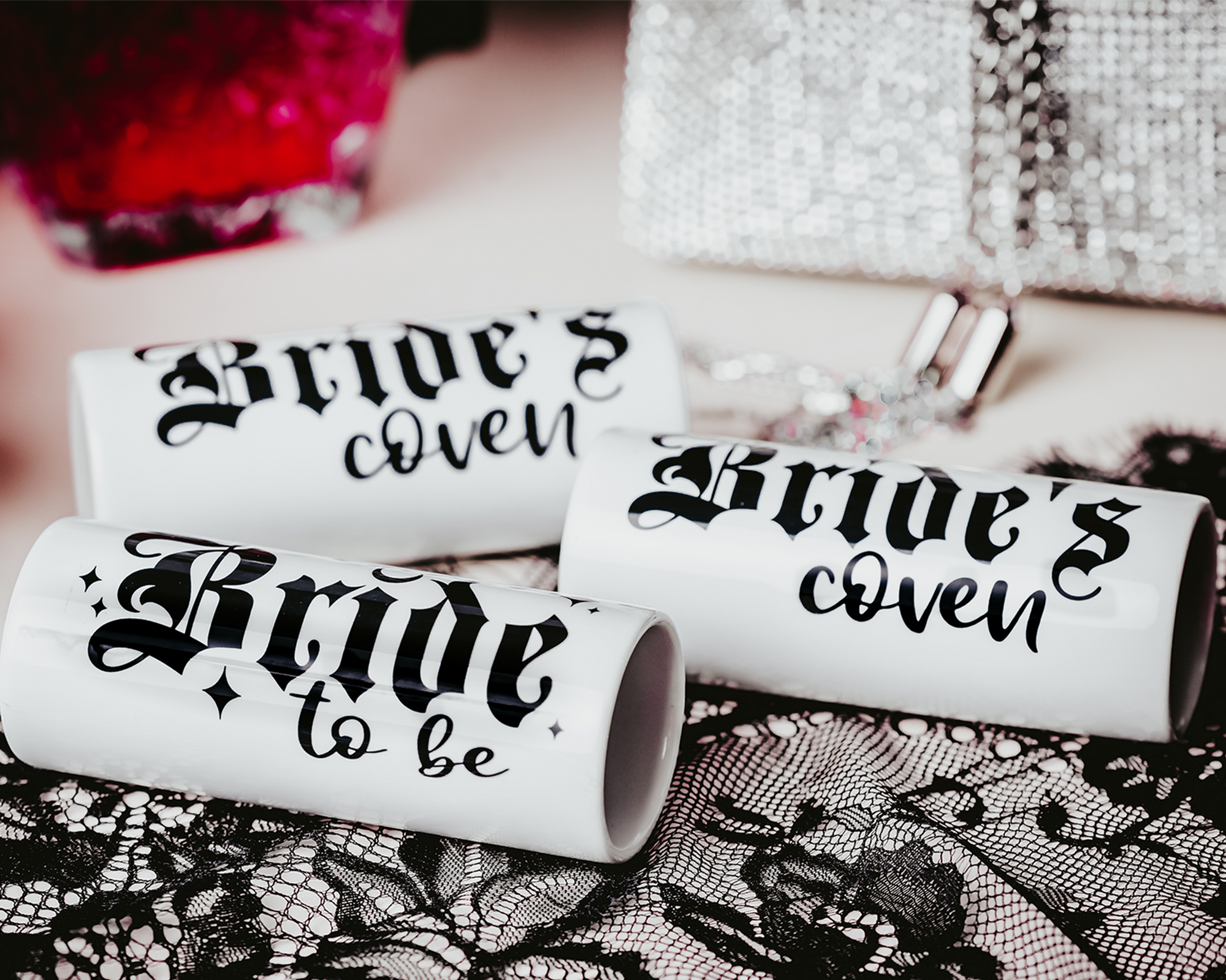 Ceramic shot glasses with gothic-style 'Bride to Be' and 'Bride's Coven' typography, perfect for a non-traditional bride and her bridal party, set against a dark, elegant backdrop.