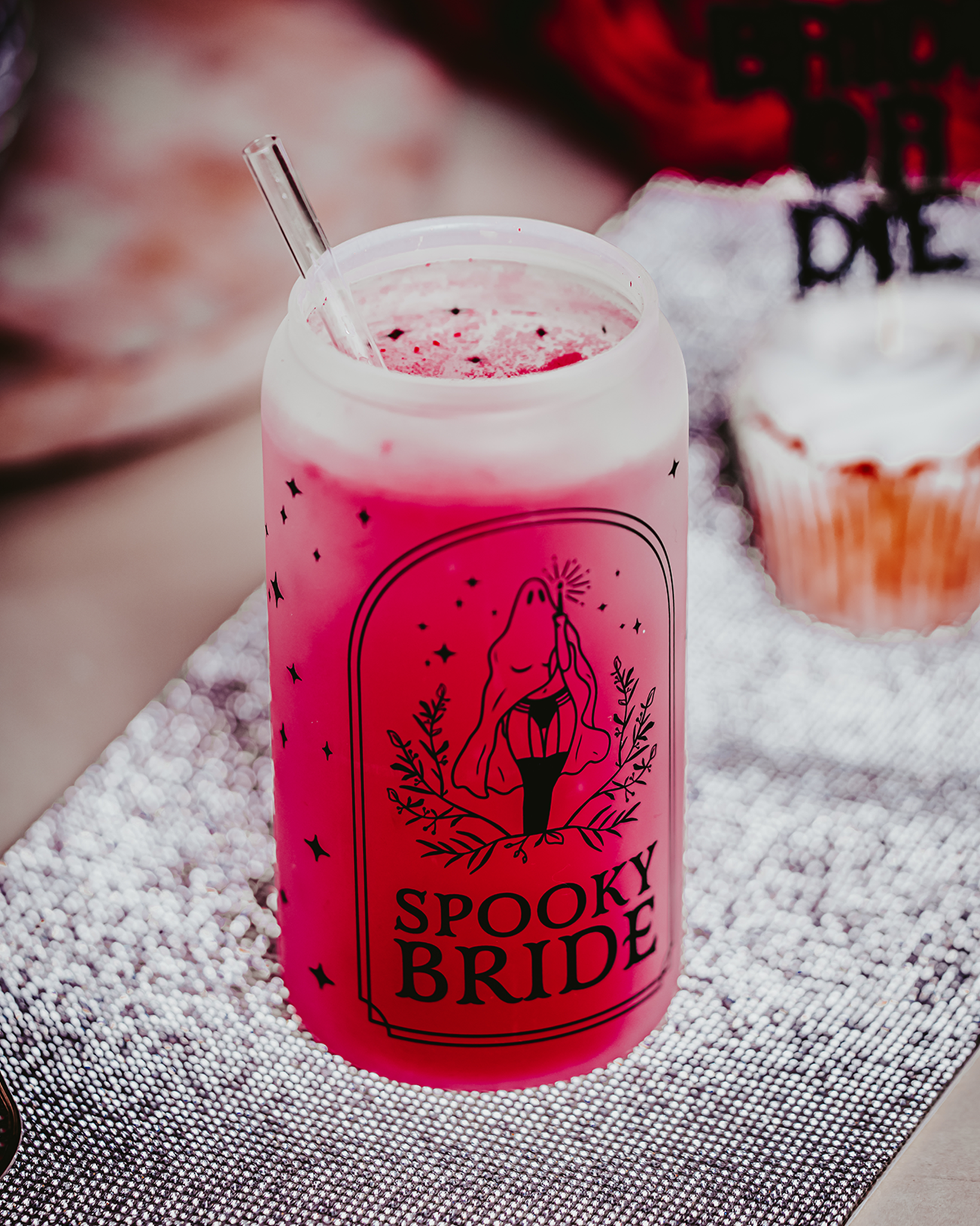 Spooky Bride Frosted Glass Can Tumbler featuring a female ghost design in stockings, with a bamboo lid and clear reusable straw, set against a gothic-themed backdrop with roses and dark décor elements."